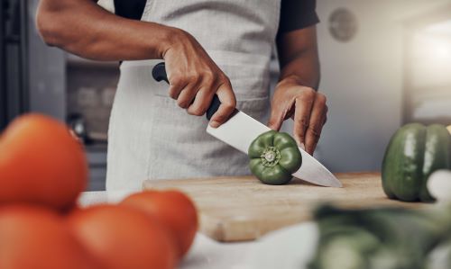 Chef cutting a bell pepper with a large knife