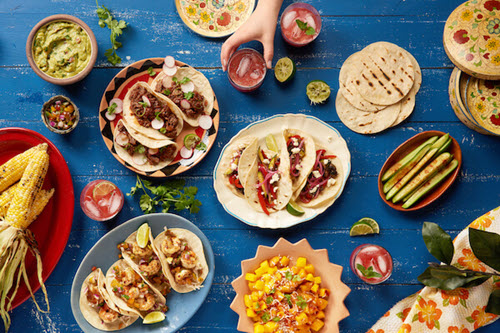 Plates full of Mexican food spread around a table